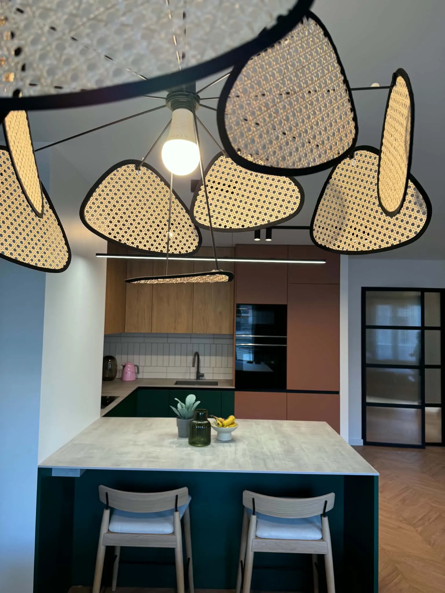 Zielona kuchnia z terakotą i lampami rattanowymi
